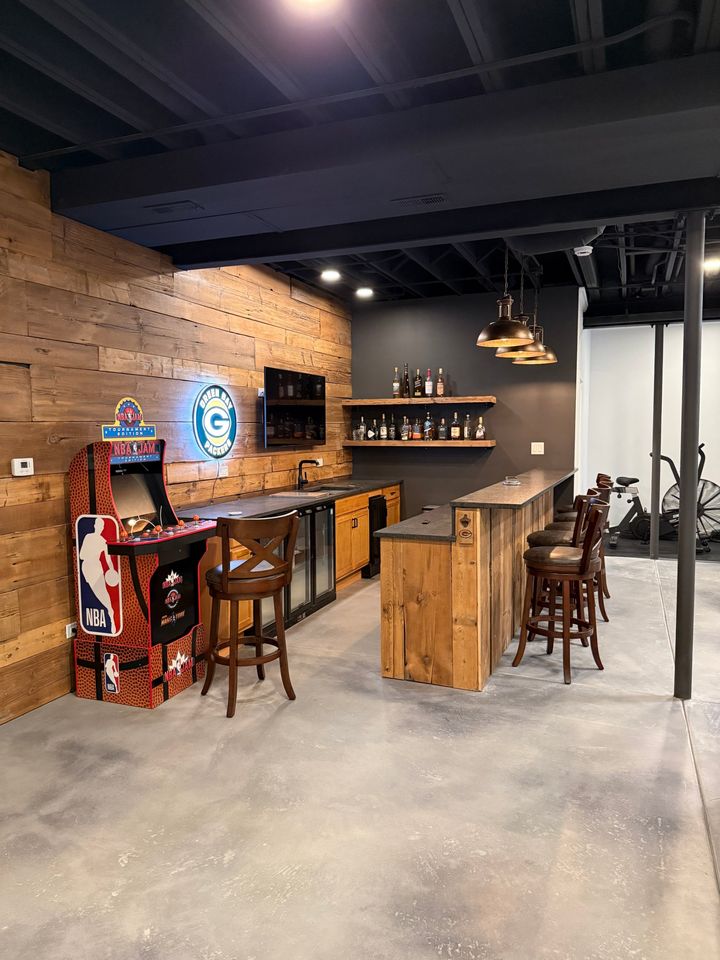 Basement bar with reclaimed wood wall, arcade cabinet and polished concrete floor