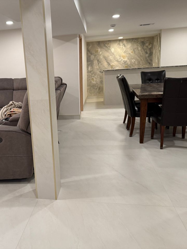 Open basement living area with large-format tile and wrapped support post