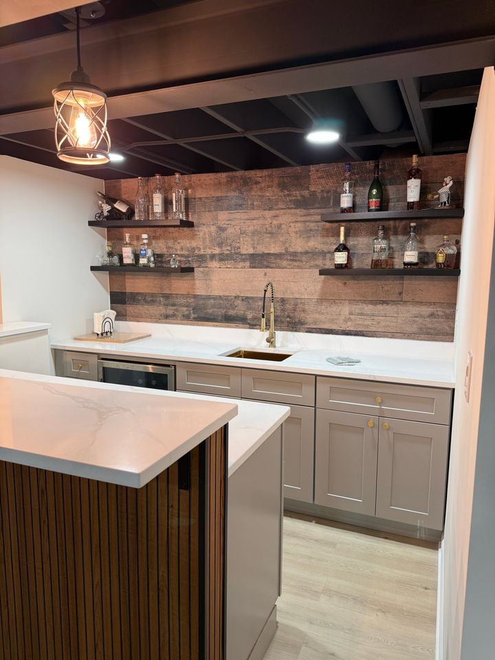 Basement wet bar with gray shaker cabinets, white quartz and wood plank backsplash