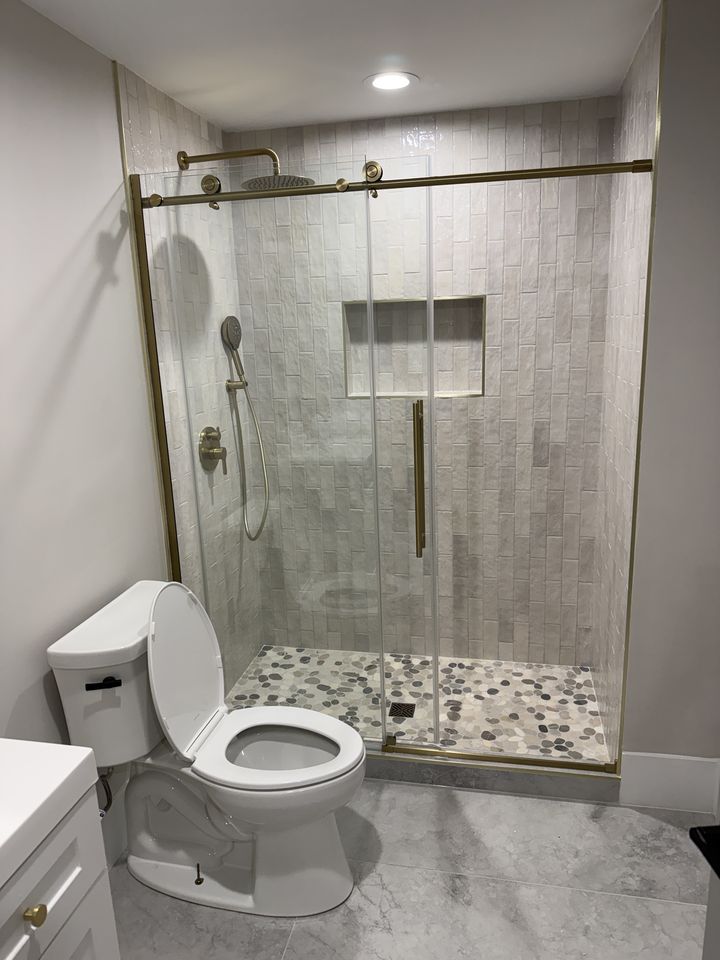 Glass shower with pebble floor and brushed gold fixtures
